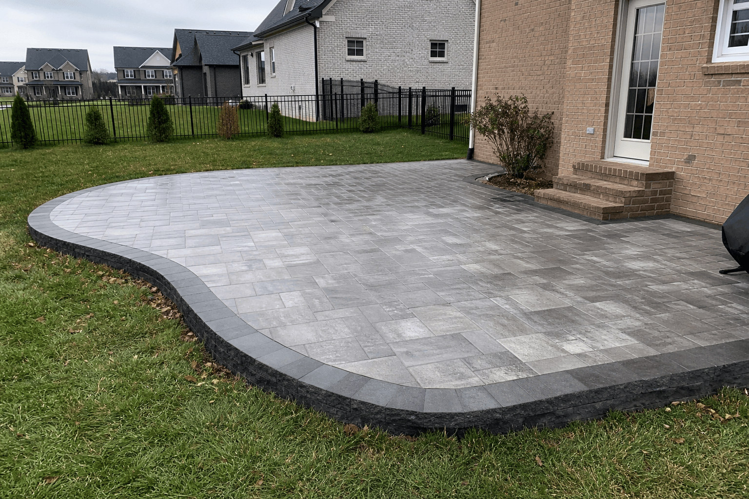 Large paver patio with landscaping and outdoor seating.